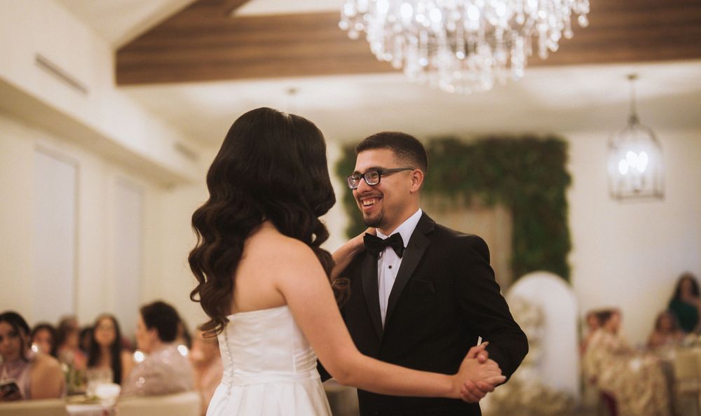 Elegant wedding reception venue with crystal chandeliers and couples dancing on a polished wood floor.