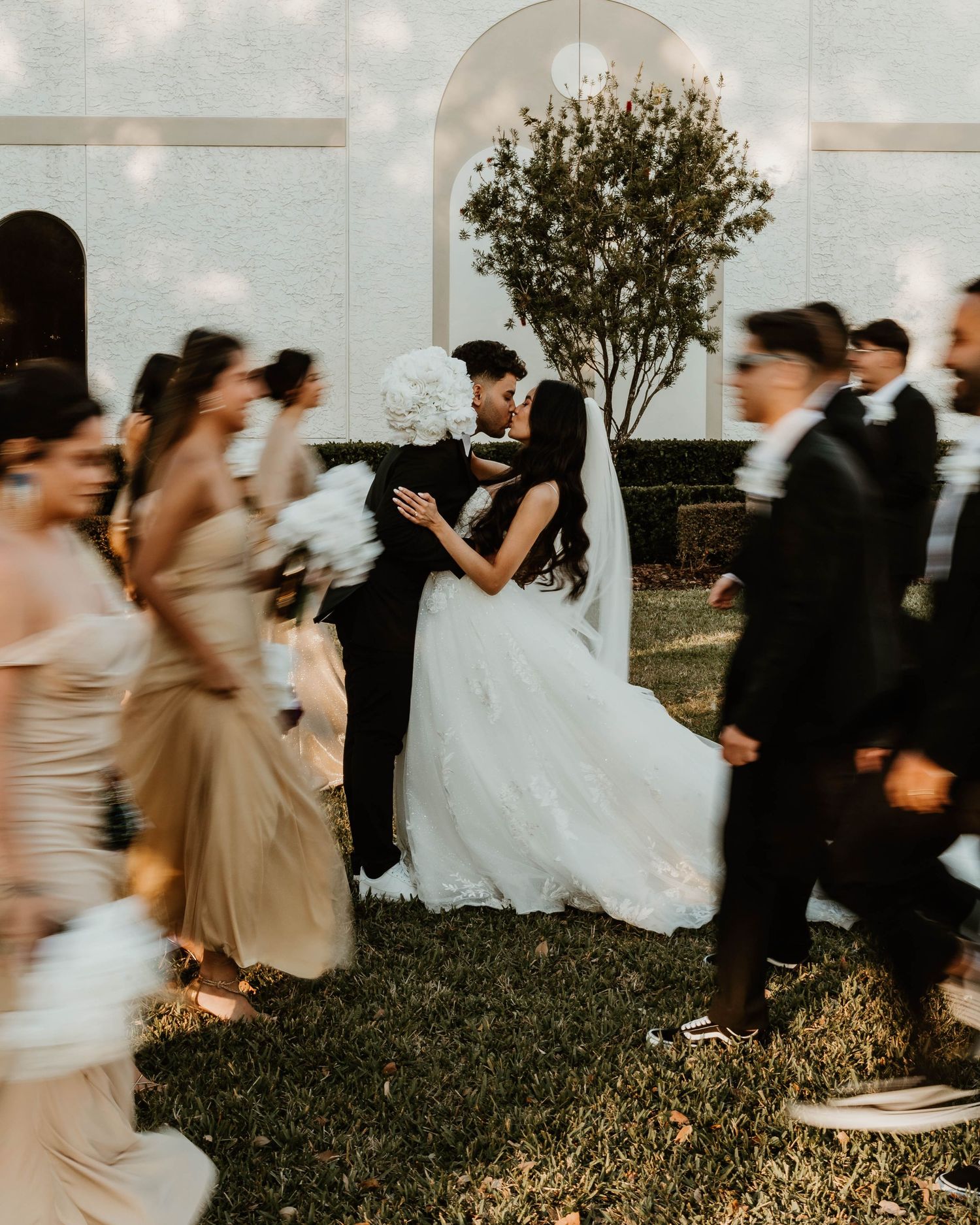 Motion-blurred wedding party dancing and celebrating outdoors.