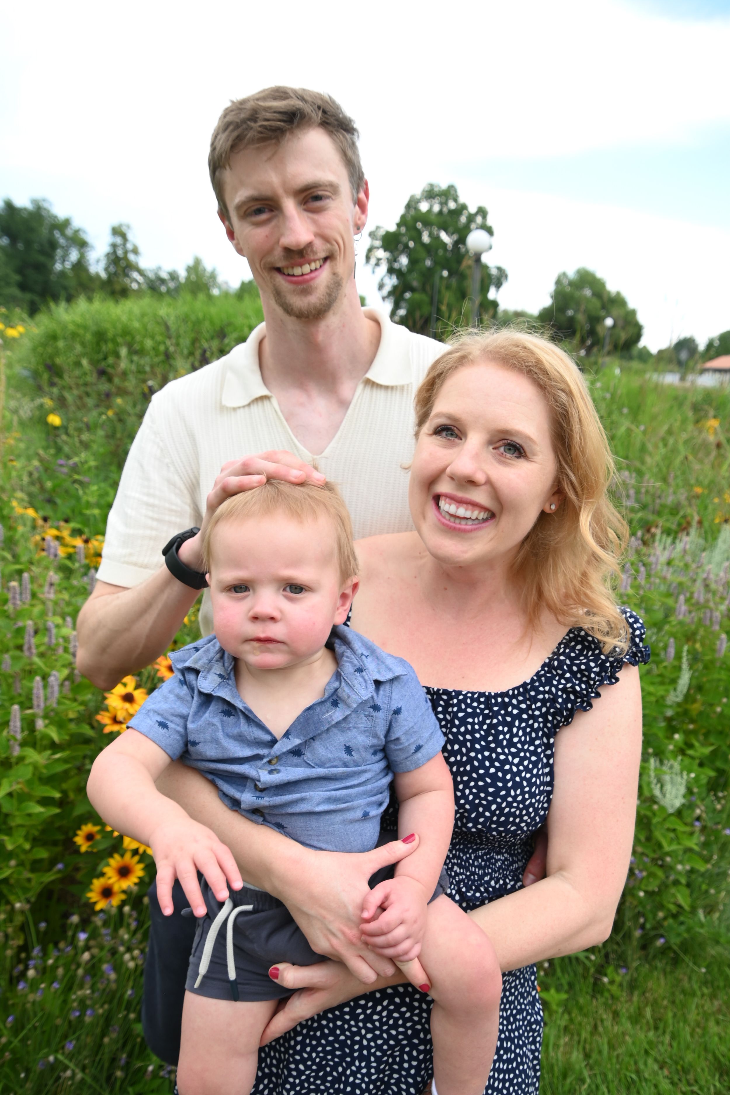 A family poses together in a wildflower garden on a sunny summer day.