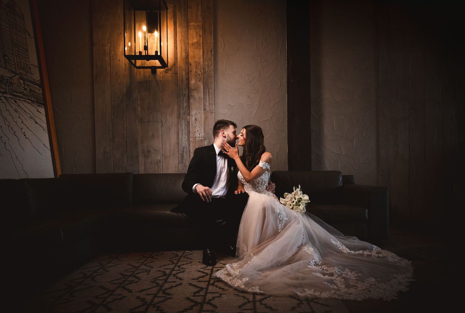 Wedding couple portrait sitting on a leather coach with romantic lighting at The Barn at Villa Venezia in Middletown NY