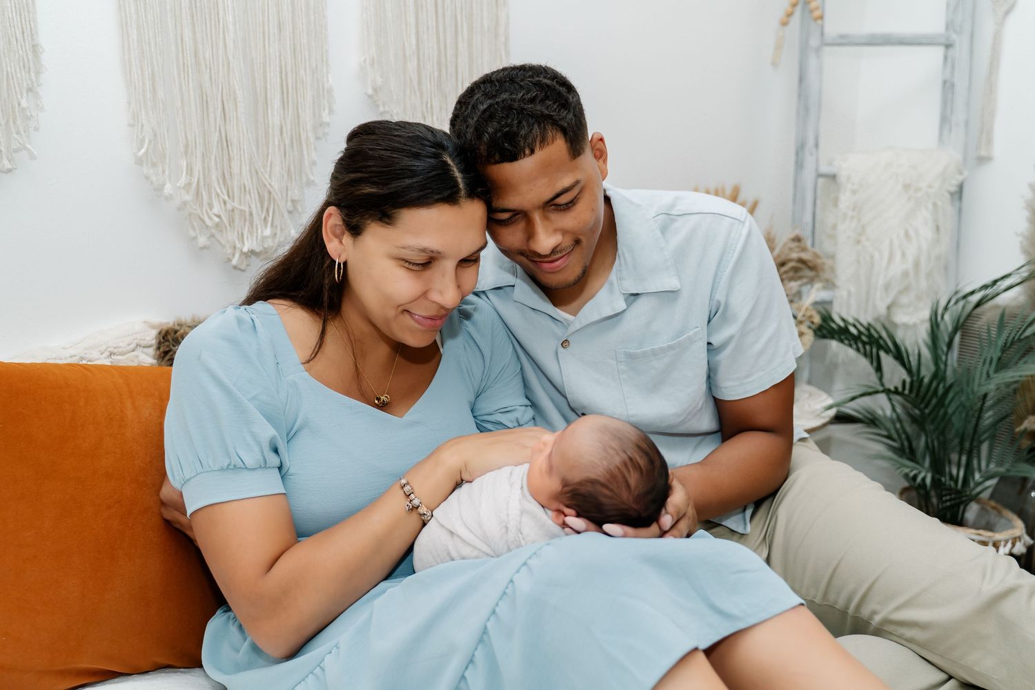 Family spending tender moments bonding with their newborn baby in a light and airy bedroom setting.