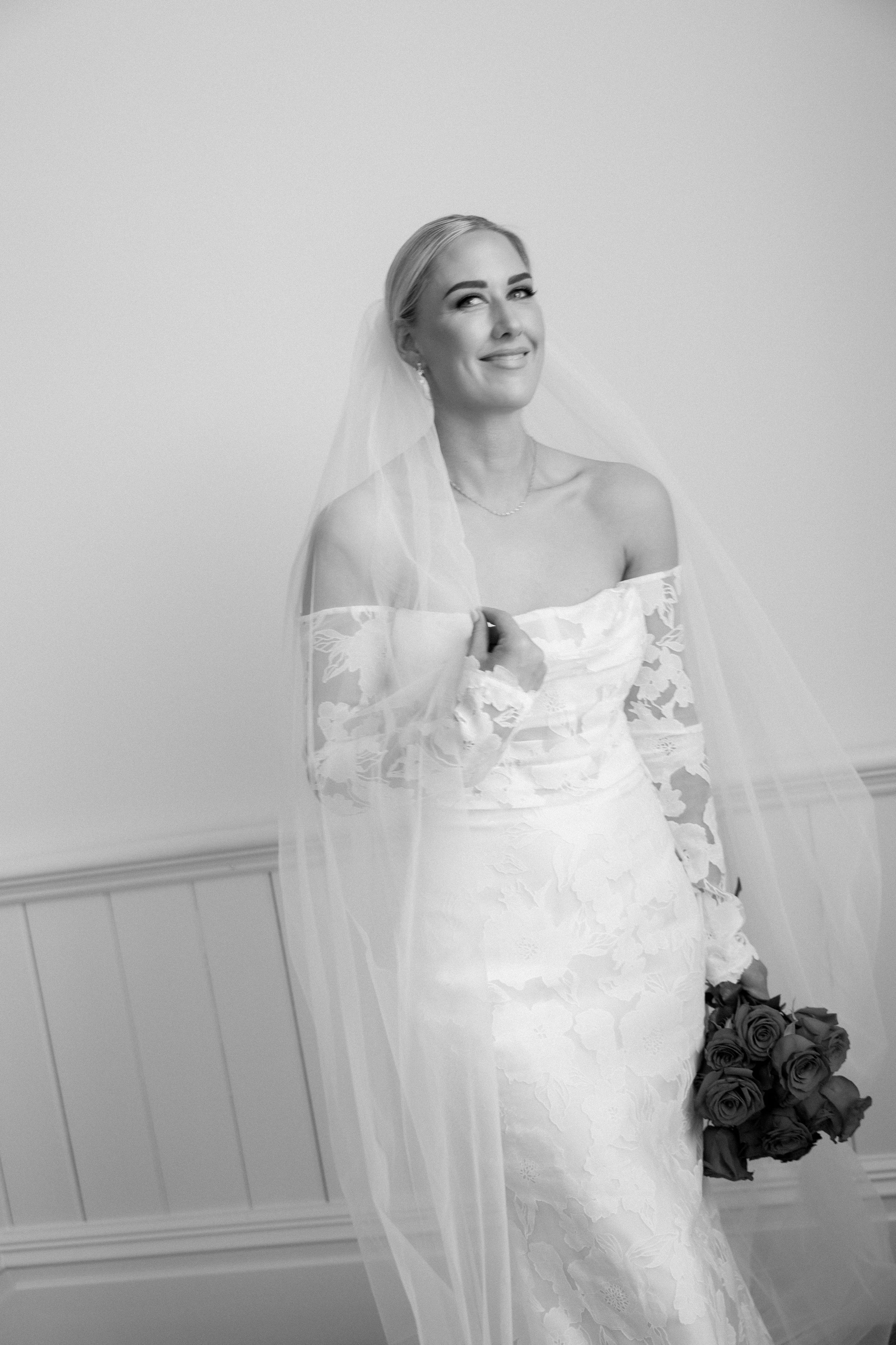 Beautiful off-shoulder lace wedding dress and veil captured in elegant black and white photography.