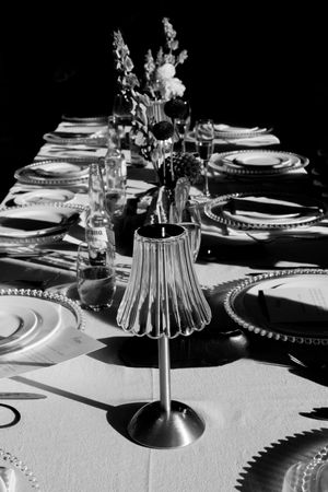 Black and white table setting with dramatic lighting showcasing elegant plates, glassware and centerpiece details.