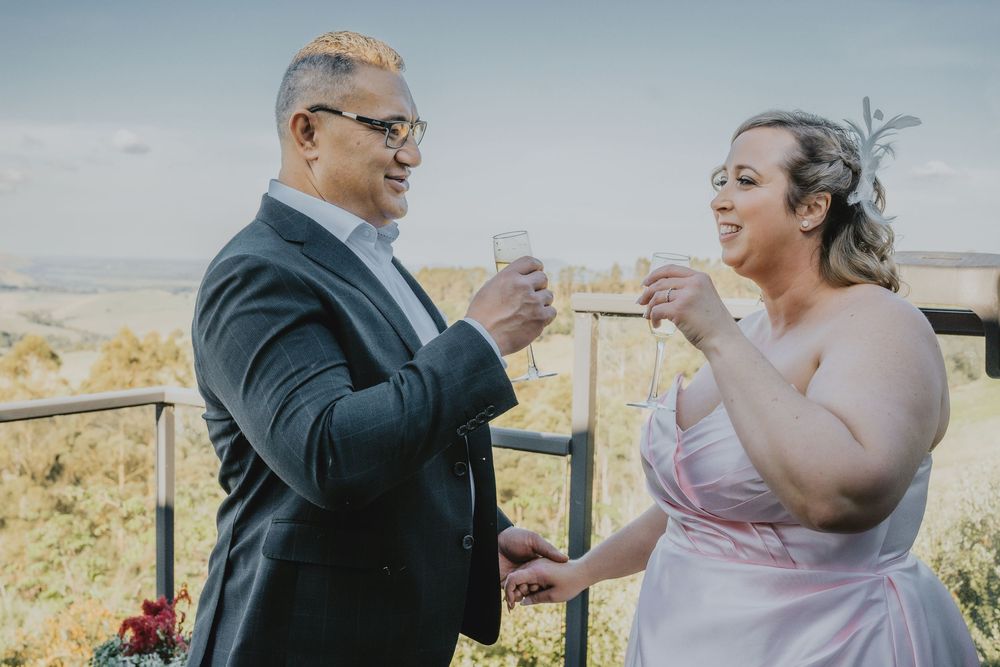 Couple sharing a heartwarming first bite of wedding cake together in a scenic outdoor setting.