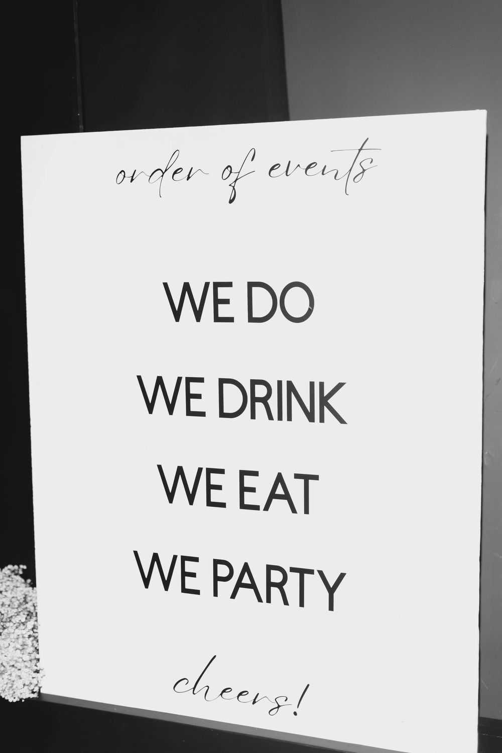 Black and white wedding sign listing order of events including We Do, We Drink, We Eat, and We Party.
