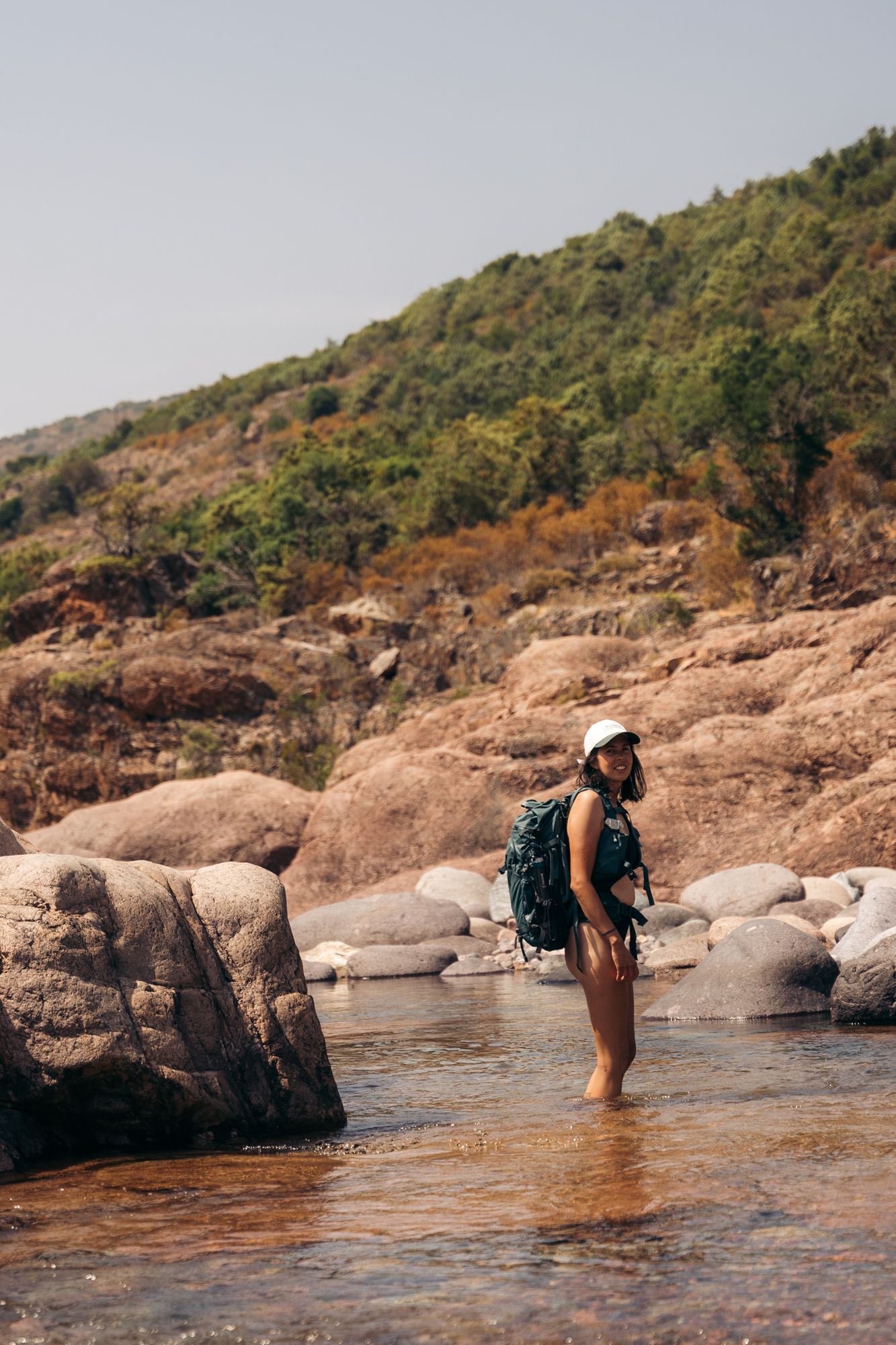 randonneuse en maillot de bain et son sac à dos de randonnée qui traverse la rivière du fango en corse