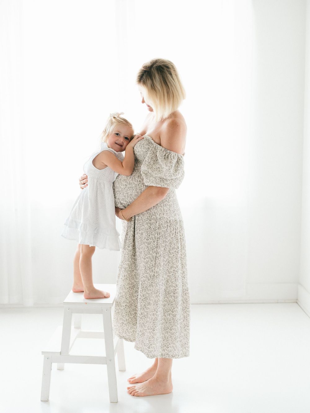 Big sister hugging her mom’s baby bump during a classic maternity session in New Jersey studio