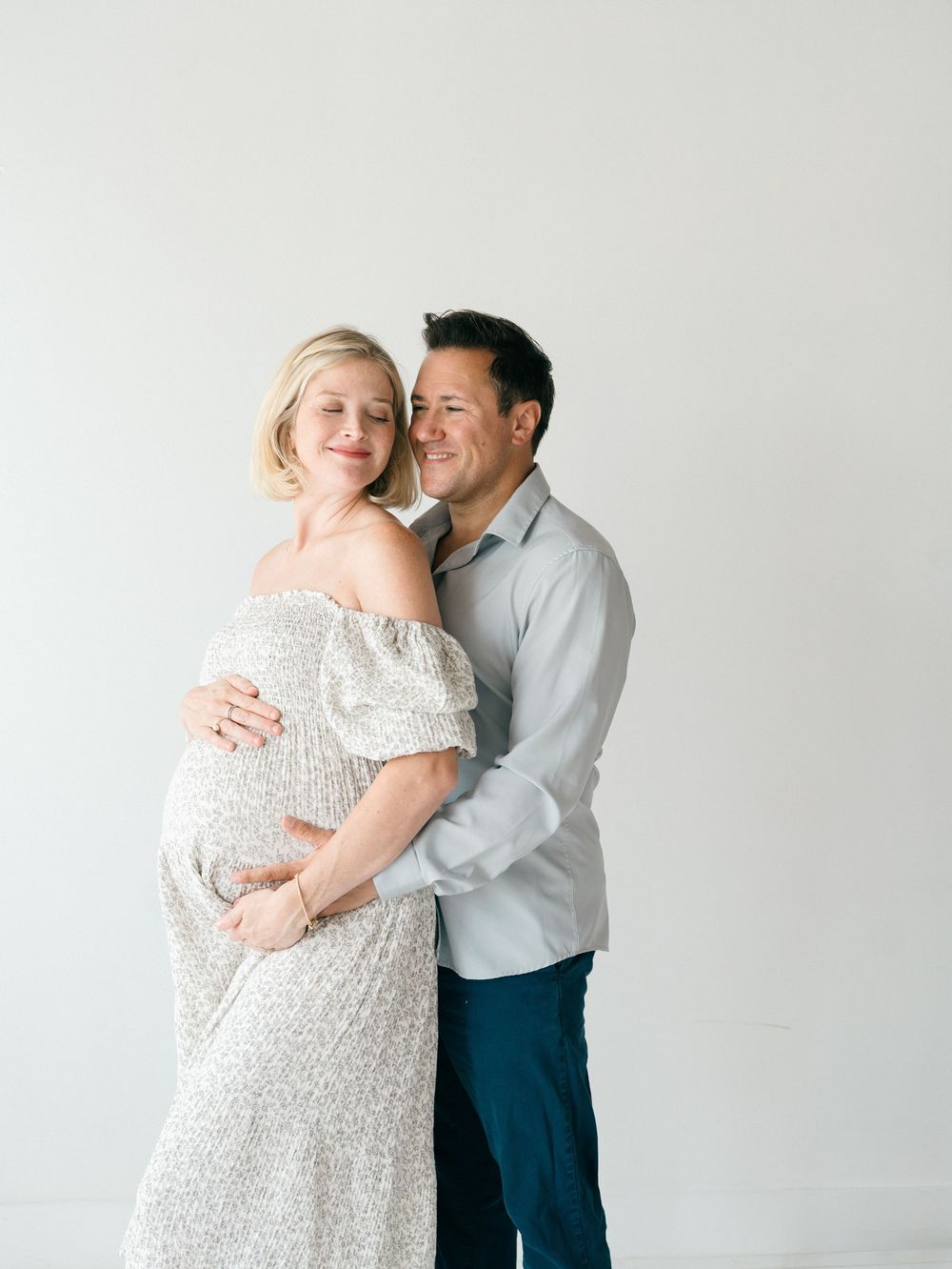 Intimate maternity portrait of expecting couple smiling together in a light-filled NJ studio