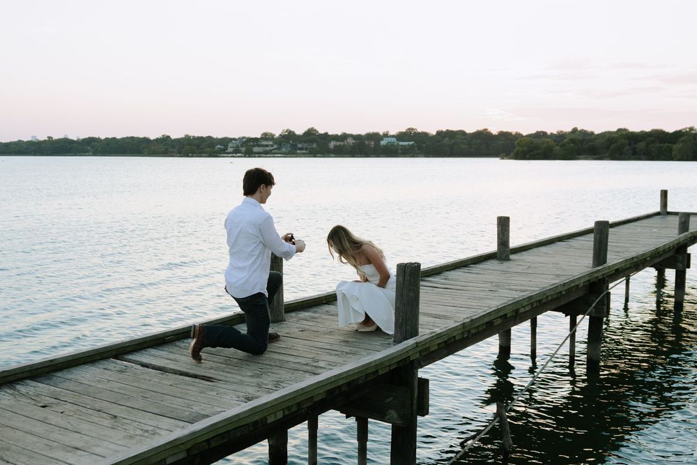 A sequence of people sitting on a wooden dock by the water during sunset creates a peaceful lakeside scene.