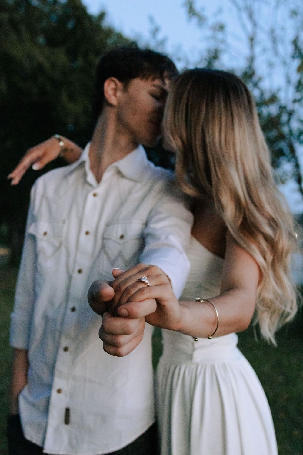 A sequence showing a couple in white outfits sharing tender moments against a natural backdrop.