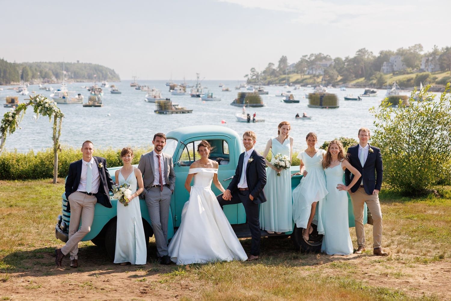 Wedding party in light blue attire poses together on a scenic coastal overlook.