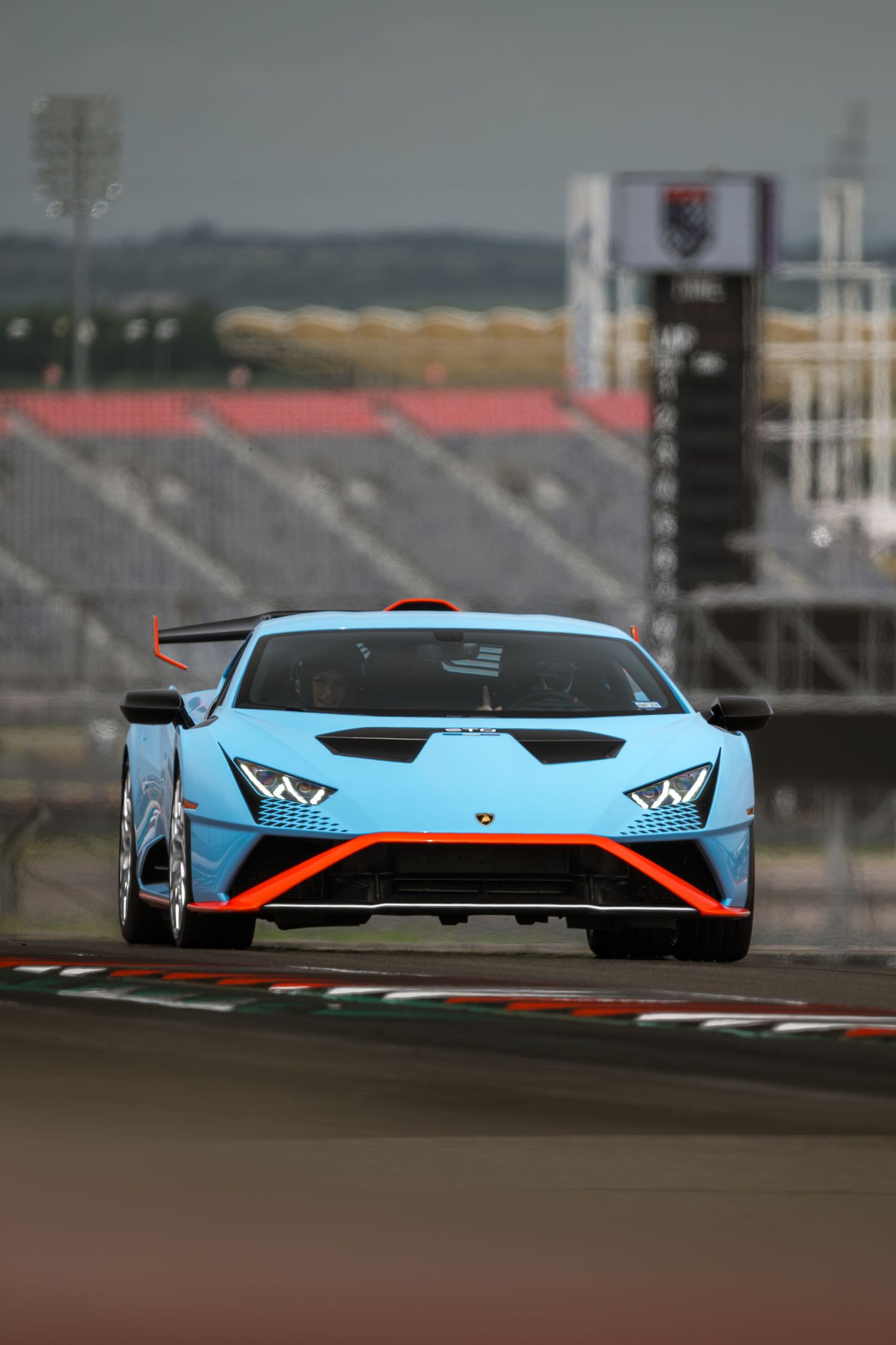 Light blue Lamborghini race car with orange accents on a racing circuit.