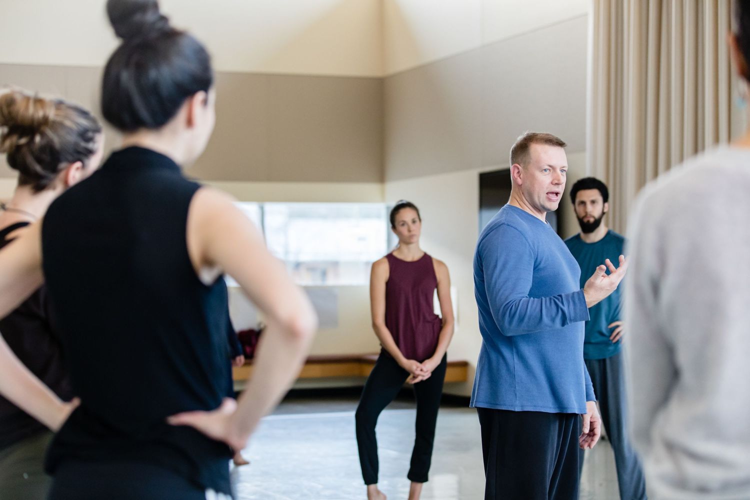 A group of people gathered in a bright fitness studio space during an indoor wellness class or training session.