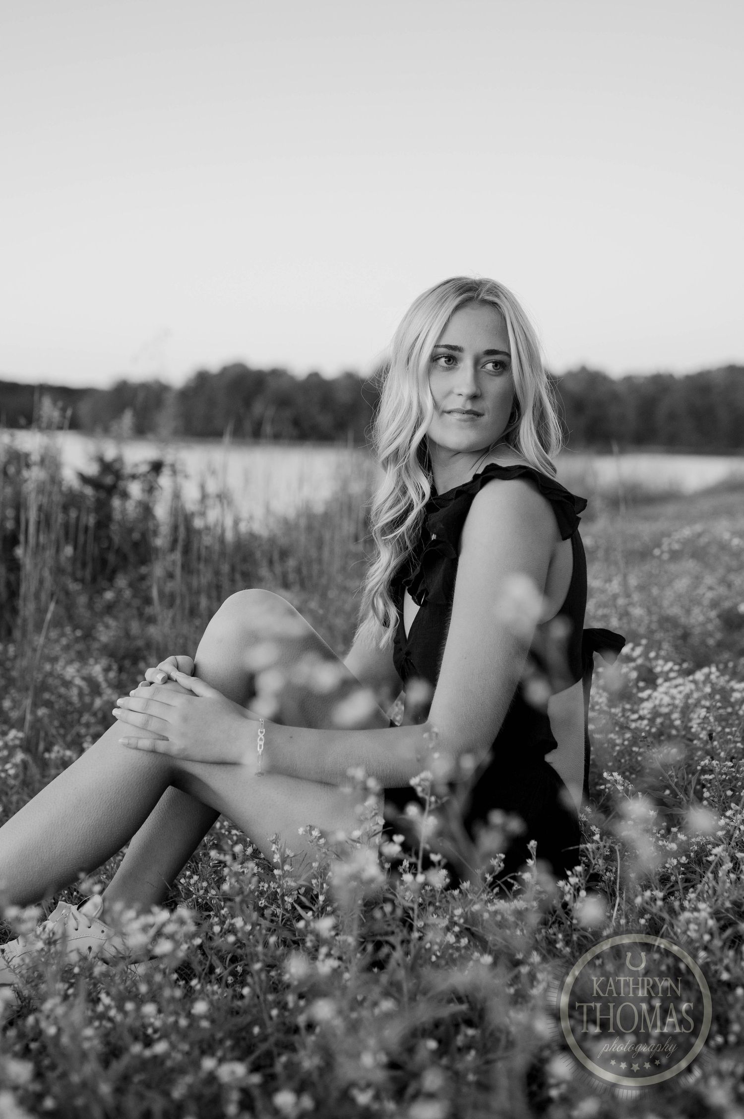 Black and white artistic portrait in blooming meadow with water view.