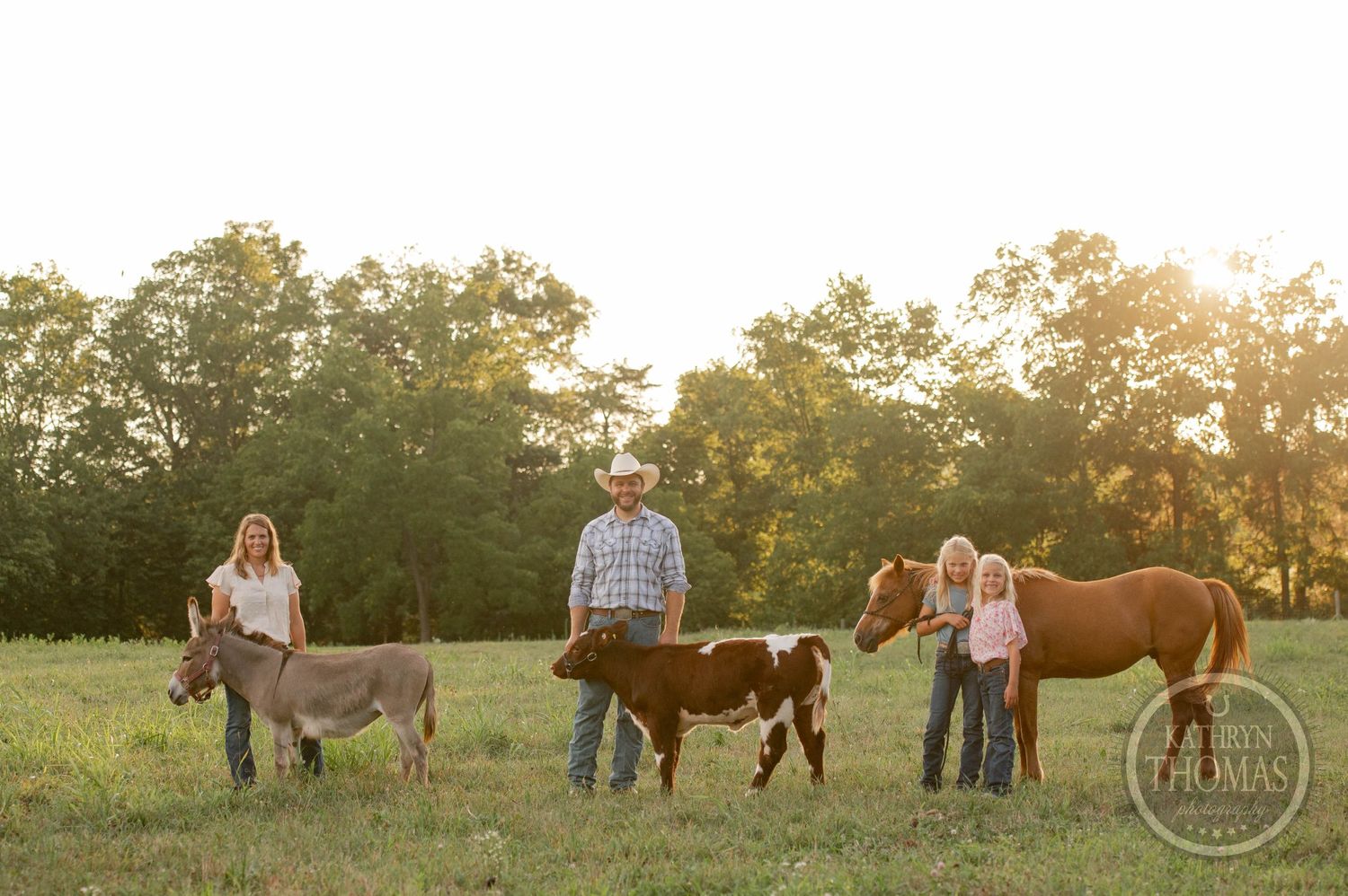 Farm family poses with their livestock in a sunlit pasture during golden hour.