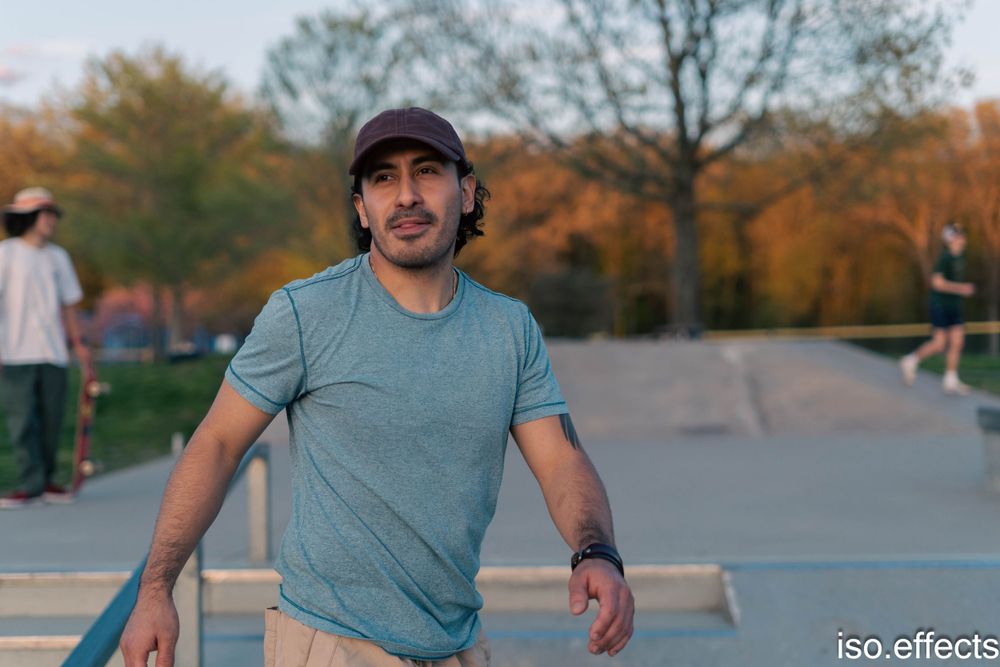 Skateboarder in grey t-shirt standing at a skate park during autumn.