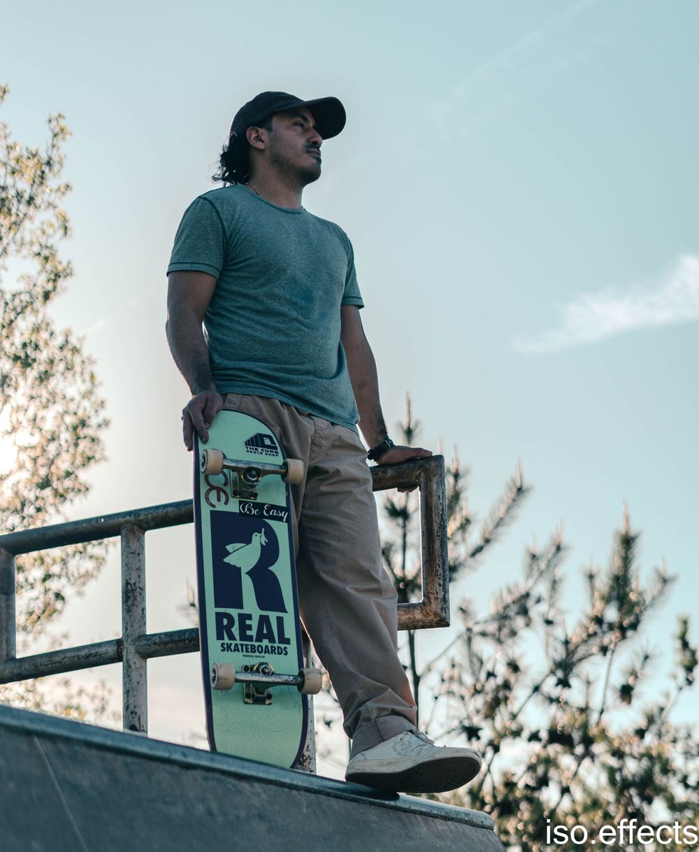 Low-angle shot of skateboarder holding Real skateboard deck on top of ramp.