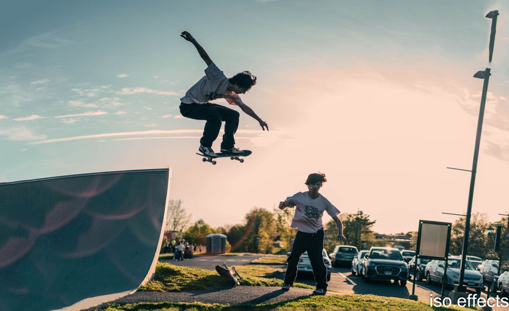 Action shot of skater performing jump trick on ramp with sunset backdrop.