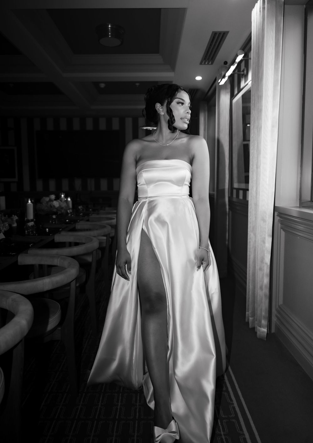 A strapless white satin gown with dramatic side slit is showcased in an elegant black and white composition.