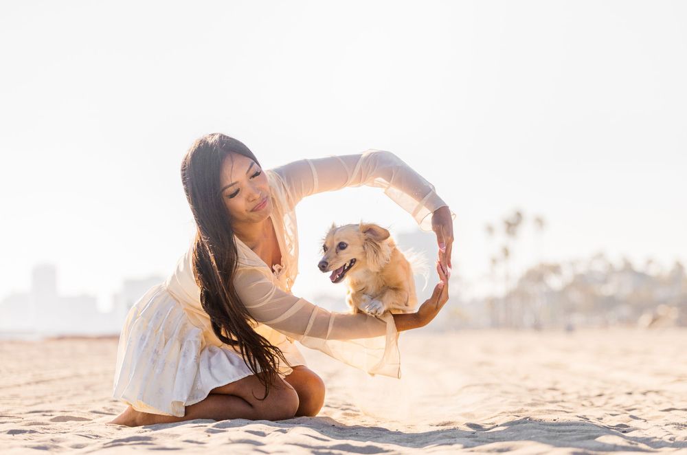 A person in white clothing lying on a sandy beach at sunset with a glowing golden backlight.