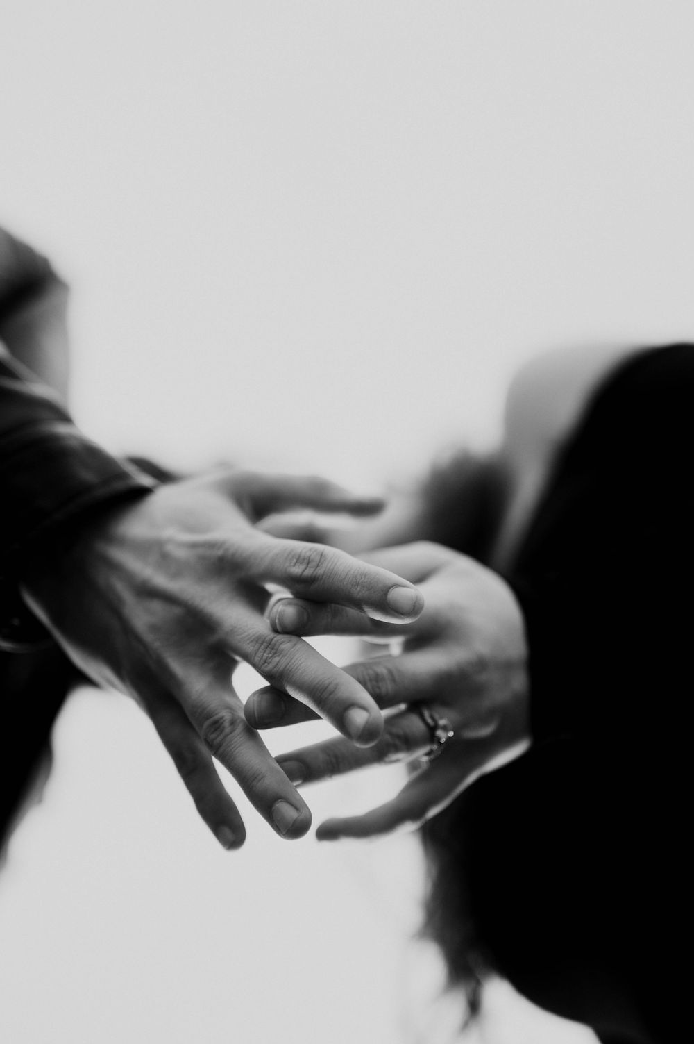 Black and white close-up of hands exchanging rings during wedding ceremony.