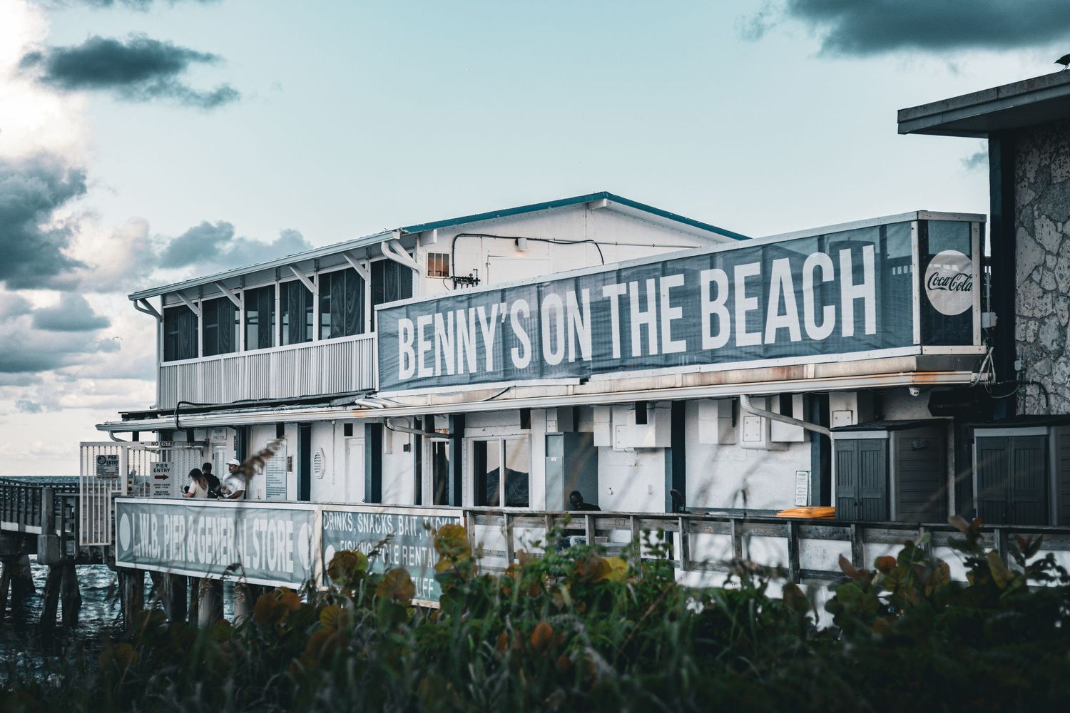 Beachside restaurant called Benny's on the Beach with a weathered exterior and ocean view deck.