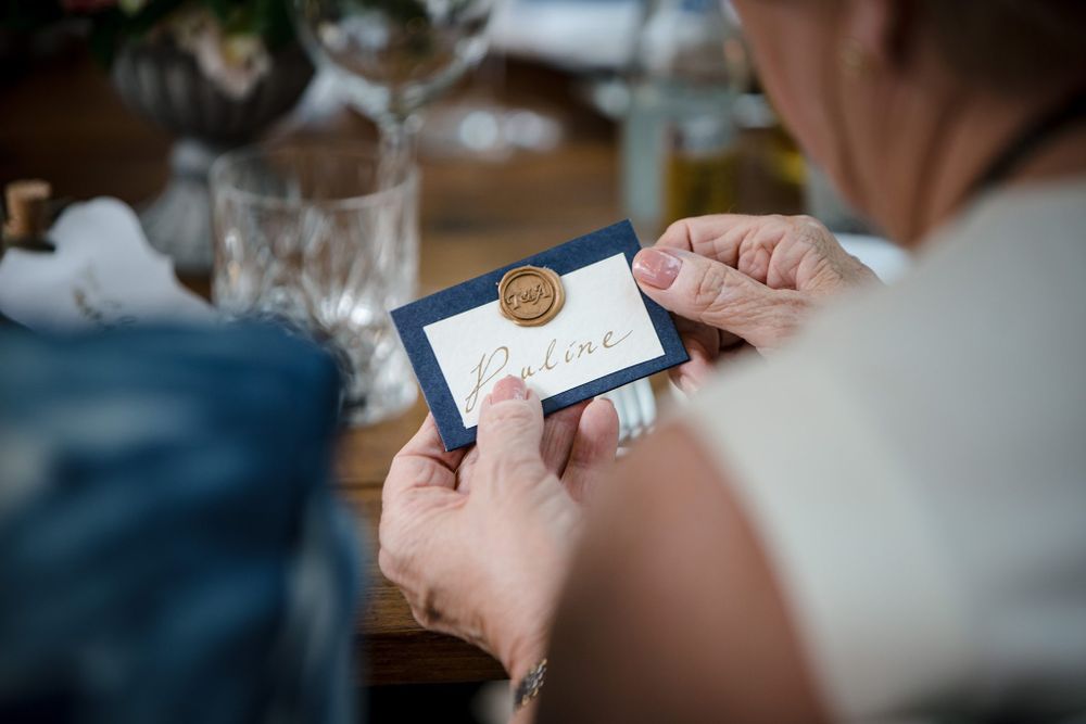 Someone holds a small white place card at The Halifax Club with golden wax seal at an elegant table setting.