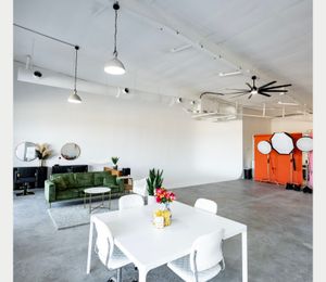 Spacious photography studio with white walls, concrete floors and modern dining furniture.