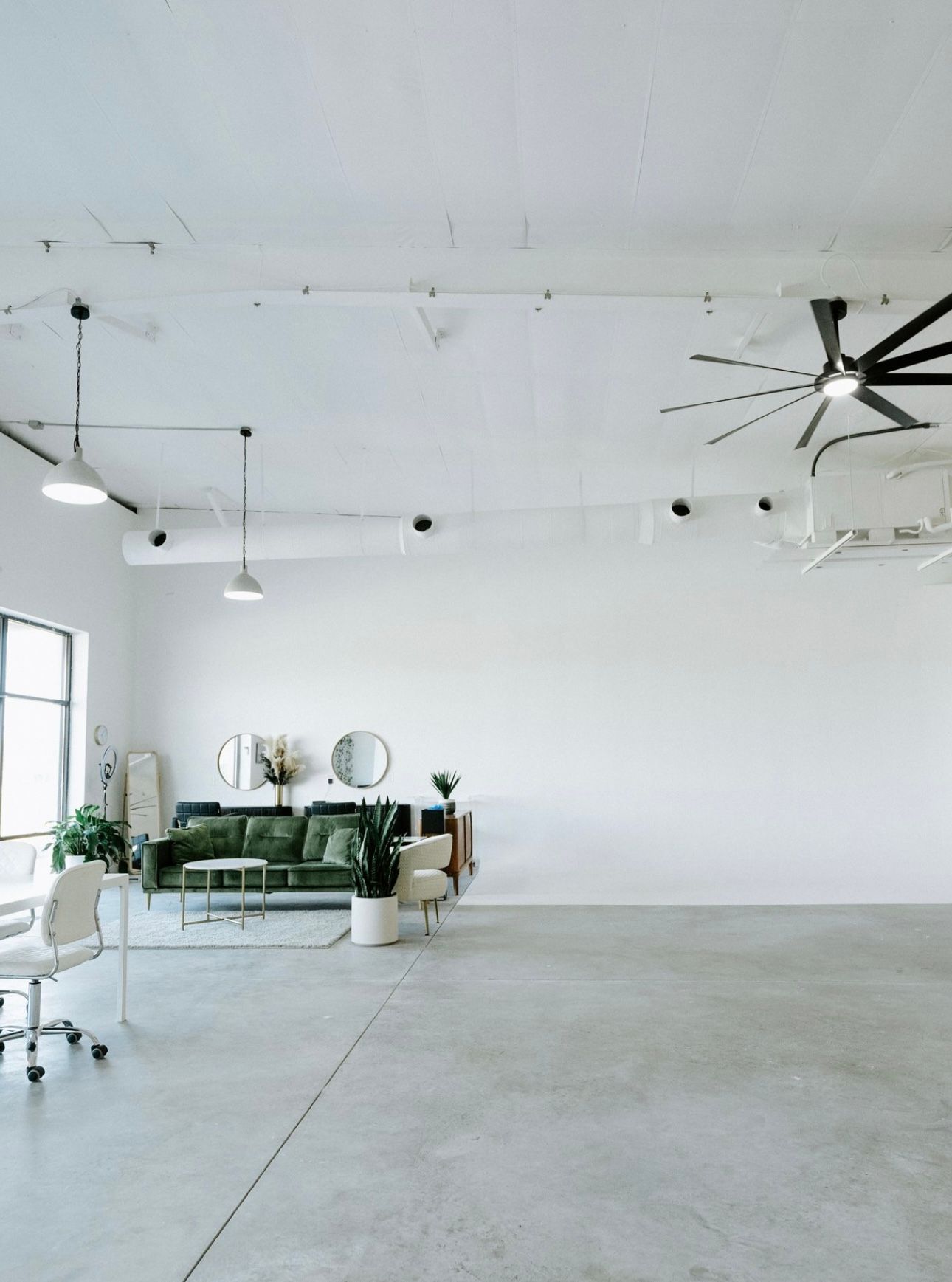 Large empty studio with white walls, concrete floors and industrial ceiling fixtures.