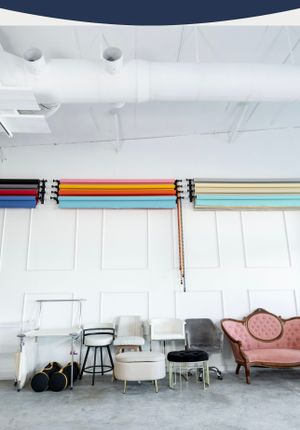 Photography studio with vintage furniture and colorful backdrop rolls mounted on the wall.