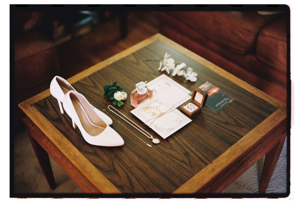 White bridal shoes and wedding details arranged on a wooden table with vintage styling.
