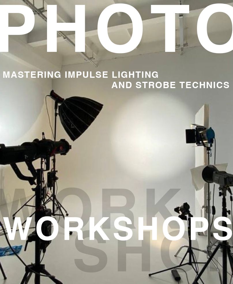 A photography studio setup with silhouettes of lighting equipment and modifiers on stands against a bright background.