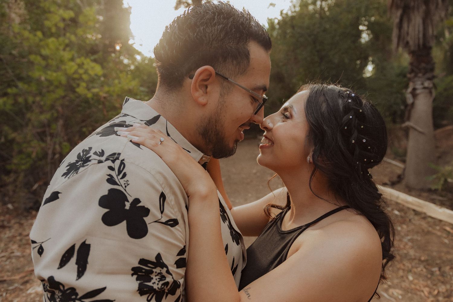 A romantic moment shared between a couple in a garden setting at sunset.