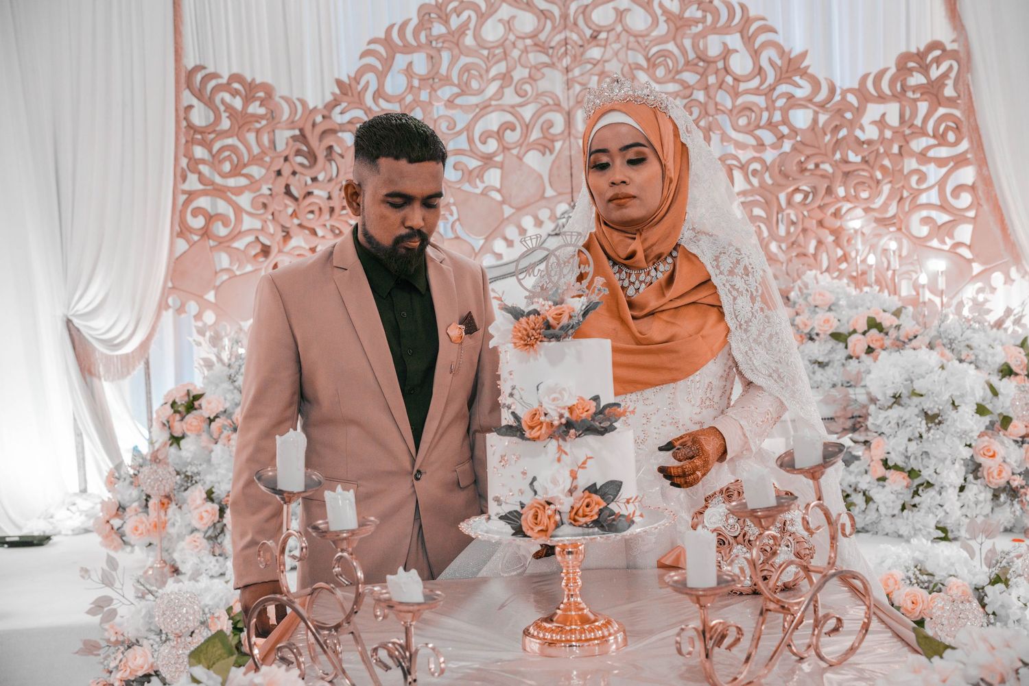 Wedding celebration with elegant peachy pink floral decorations and ornate backdrop.