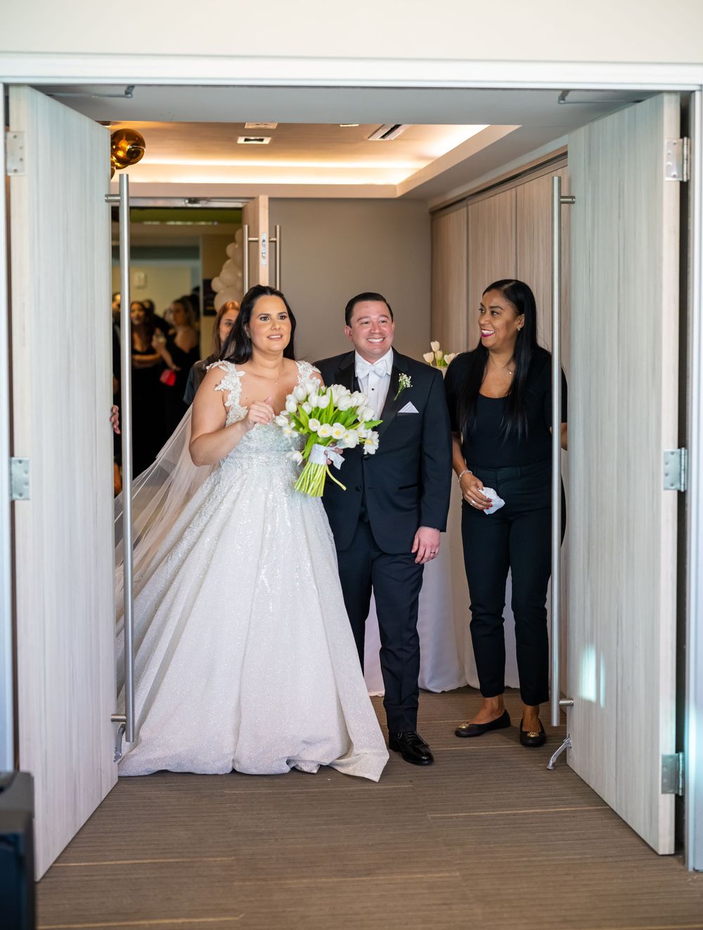 Wedding party walking through doorway in formal attire.