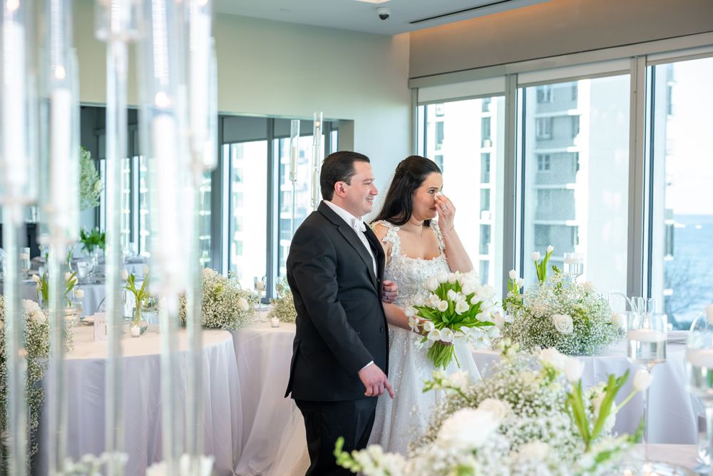 Couple admiring wedding reception decor in sunlit venue.