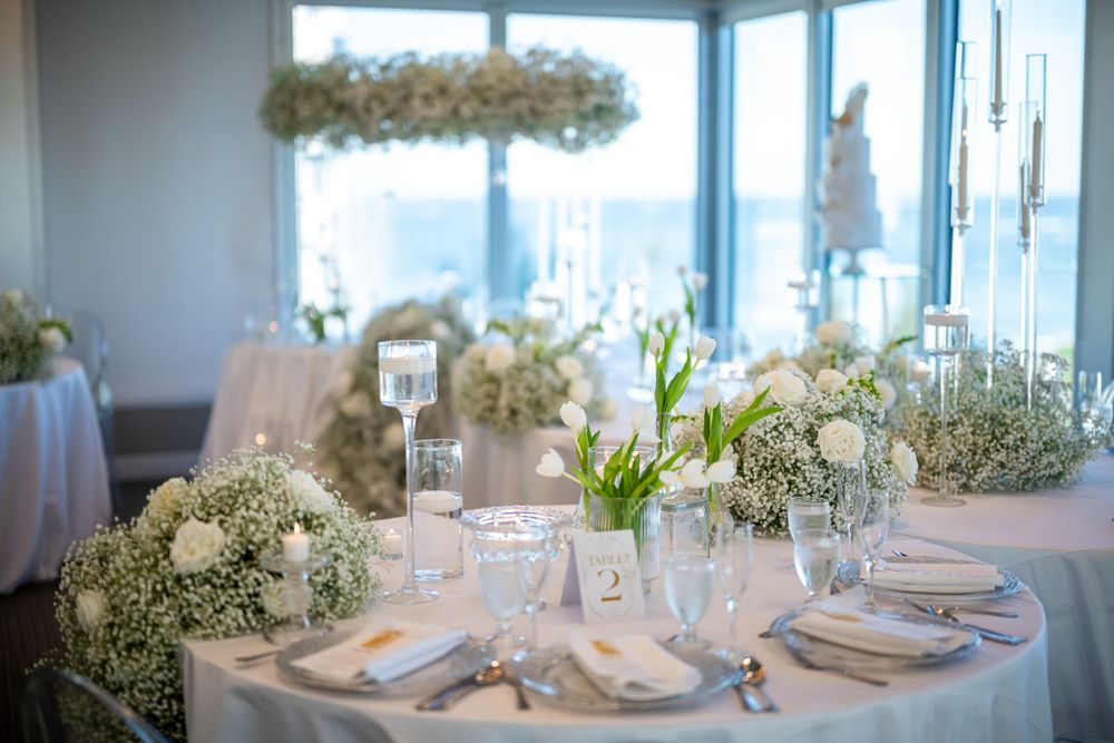 Light-filled wedding reception table with white floral centerpieces and elegant place settings.