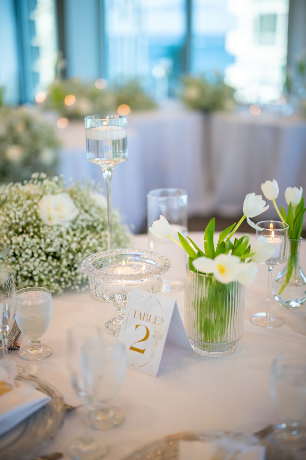 Elegant table setting with white tulips, baby's breath and table number card.