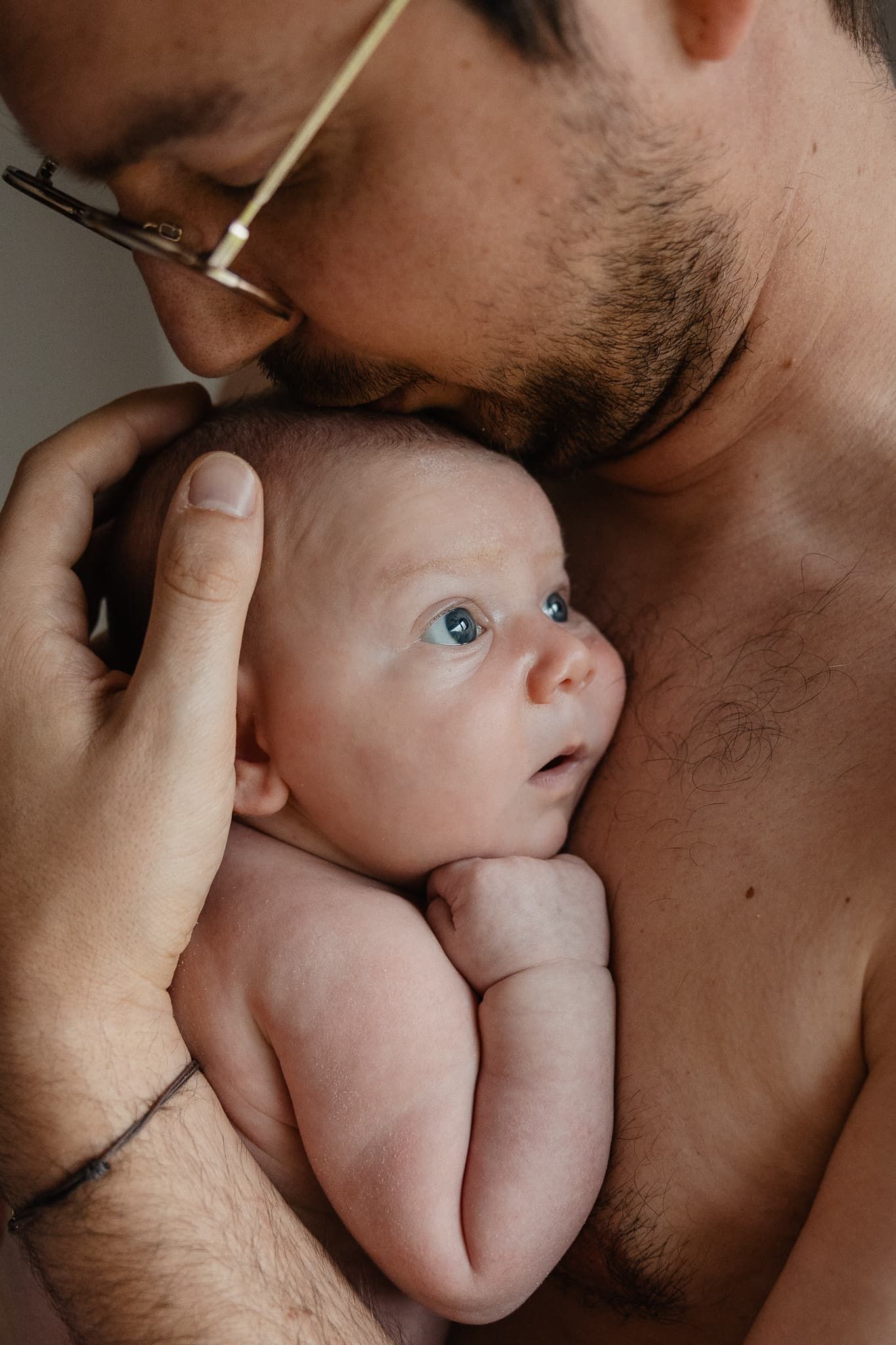 photo emouvante d'un papa en peau a peau avec son nouveau-ne lors d'un shooting naissance a domicile pres de Lille avec une photographe pro