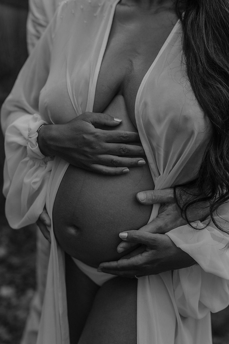 Close-up of pregnant woman holding her belly during an intimate maternity photoshoot in our habitas tulum.