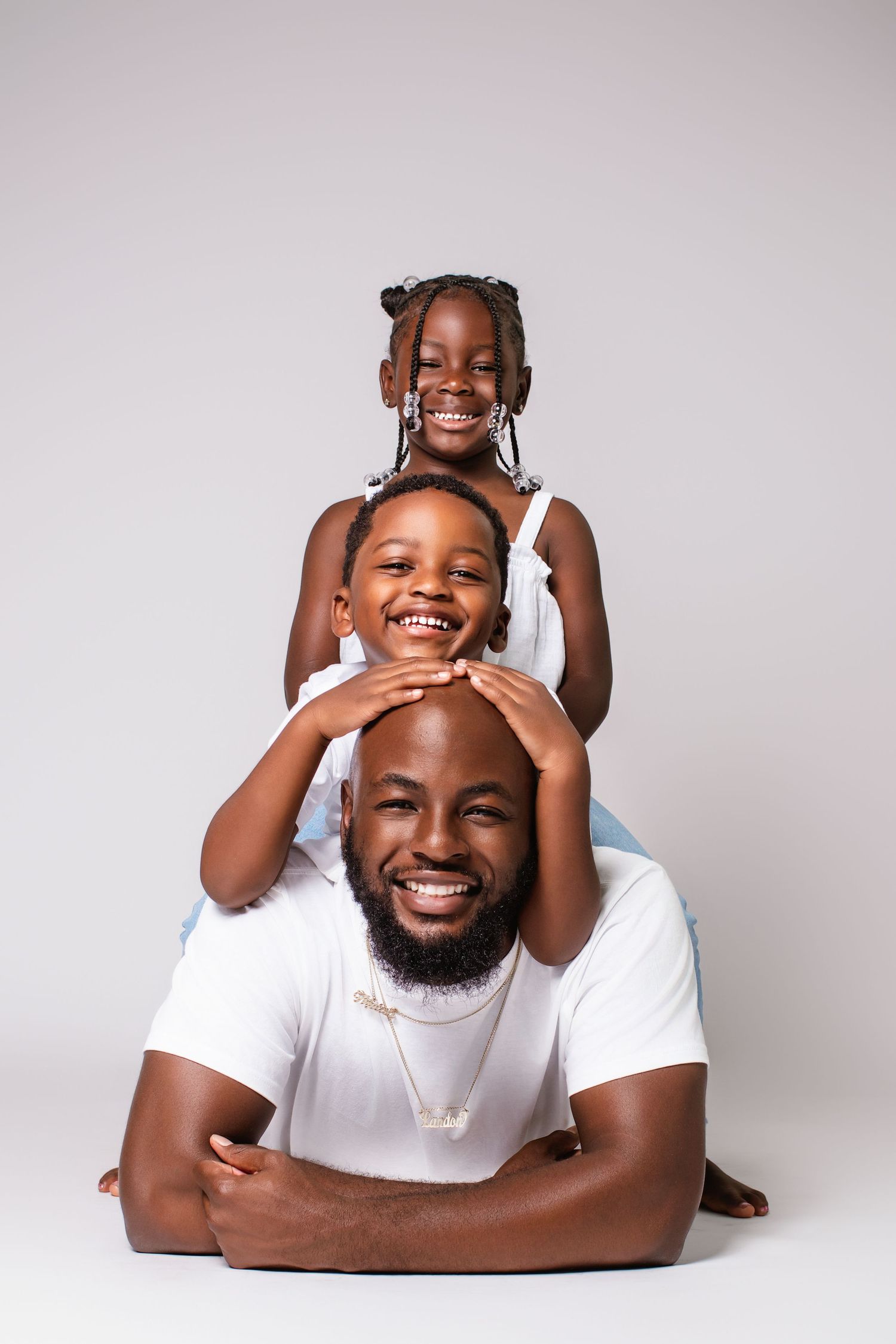 A joyful family portrait with stacked poses against a light gray studio background.