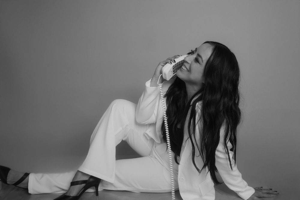Artistic black and white portrait with telephone against minimal background.