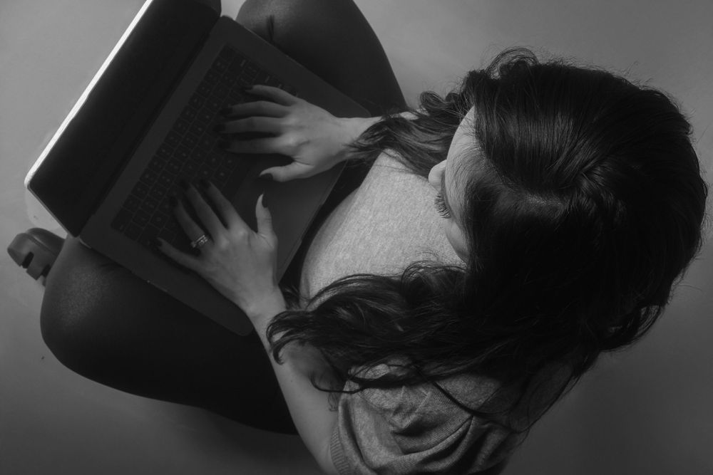 Artistic black and white photo of hands holding notebook in dramatic lighting.