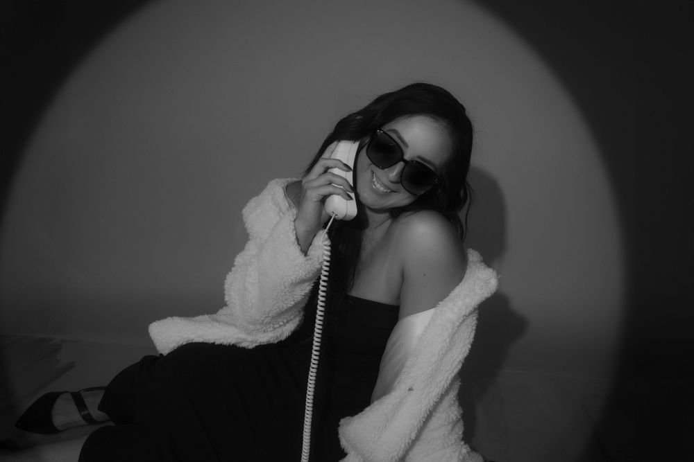 Dramatic black and white portrait with retro telephone and cozy sweater.