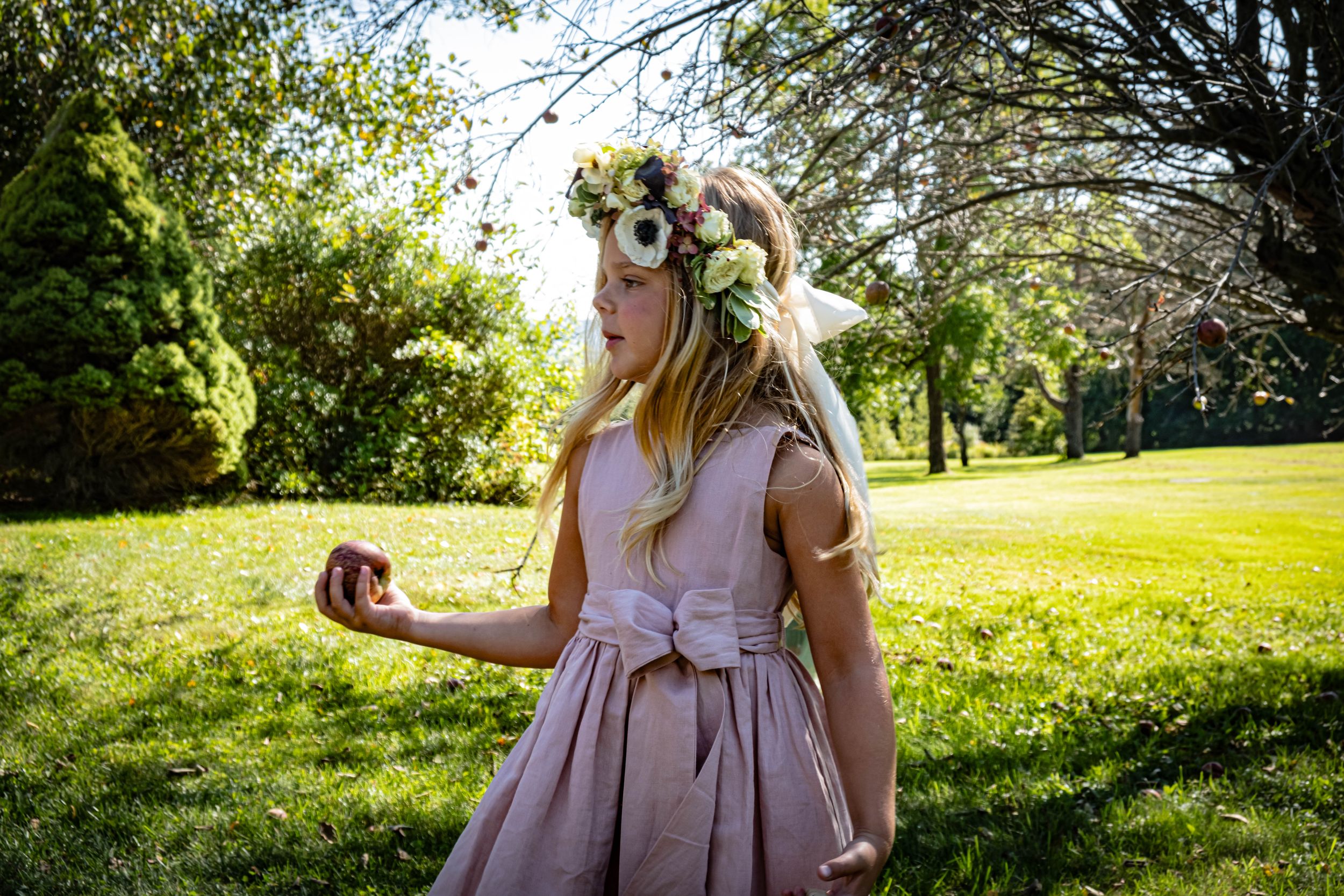Girl holding an apple in a field posing for before wedding ceremony pictures.