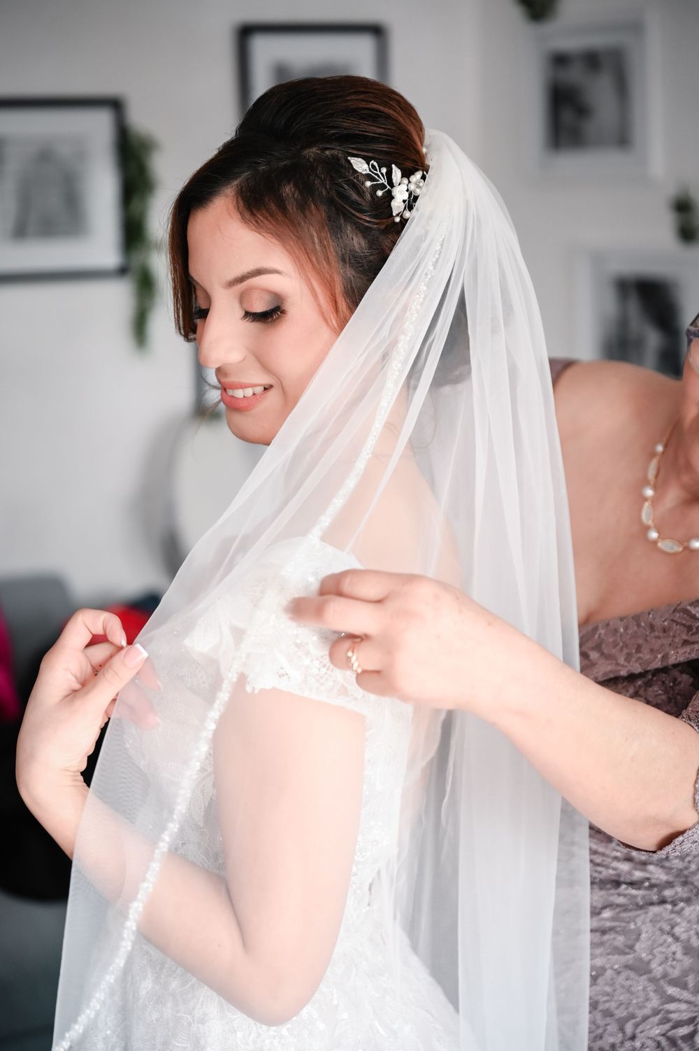 Delicate adjustments being made to a flowing white wedding veil with lace details.