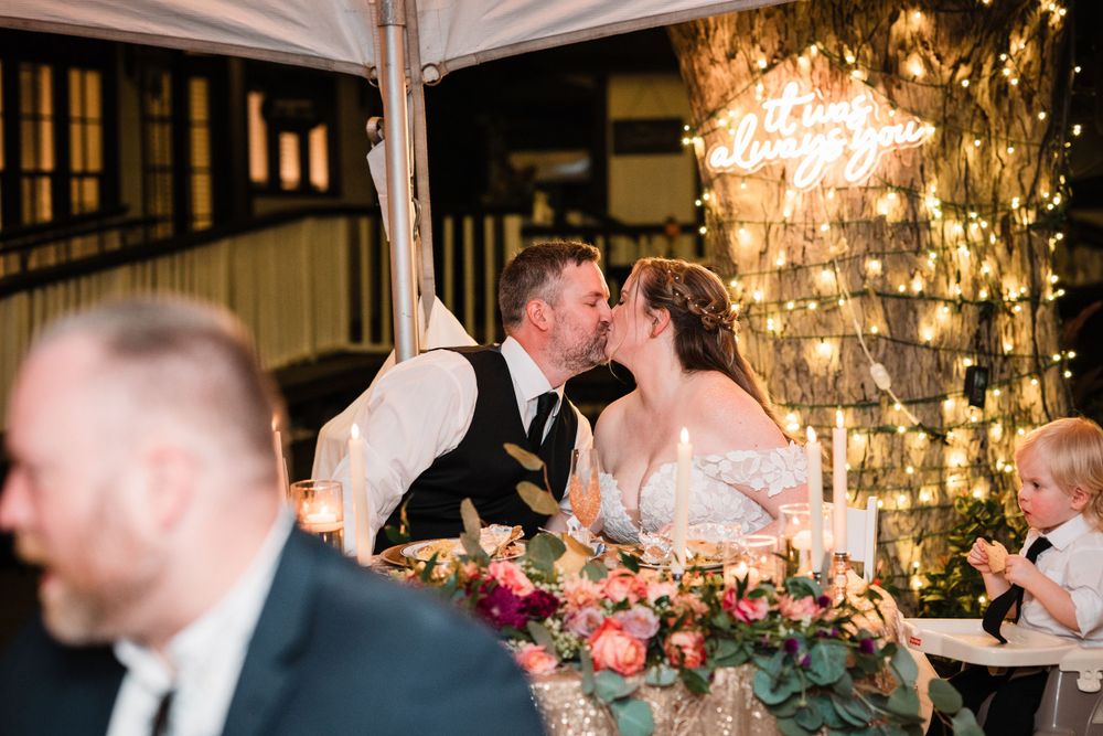 Wedding reception venue decorated with warm lighting and floral centerpieces.