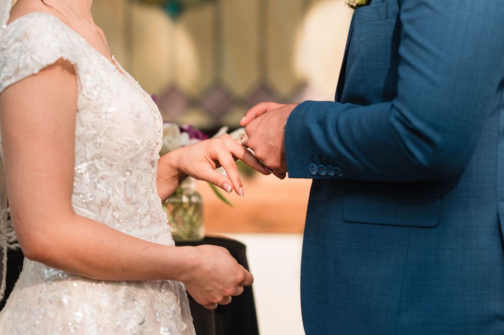 Close-up of hands showing wedding rings and lace dress details.