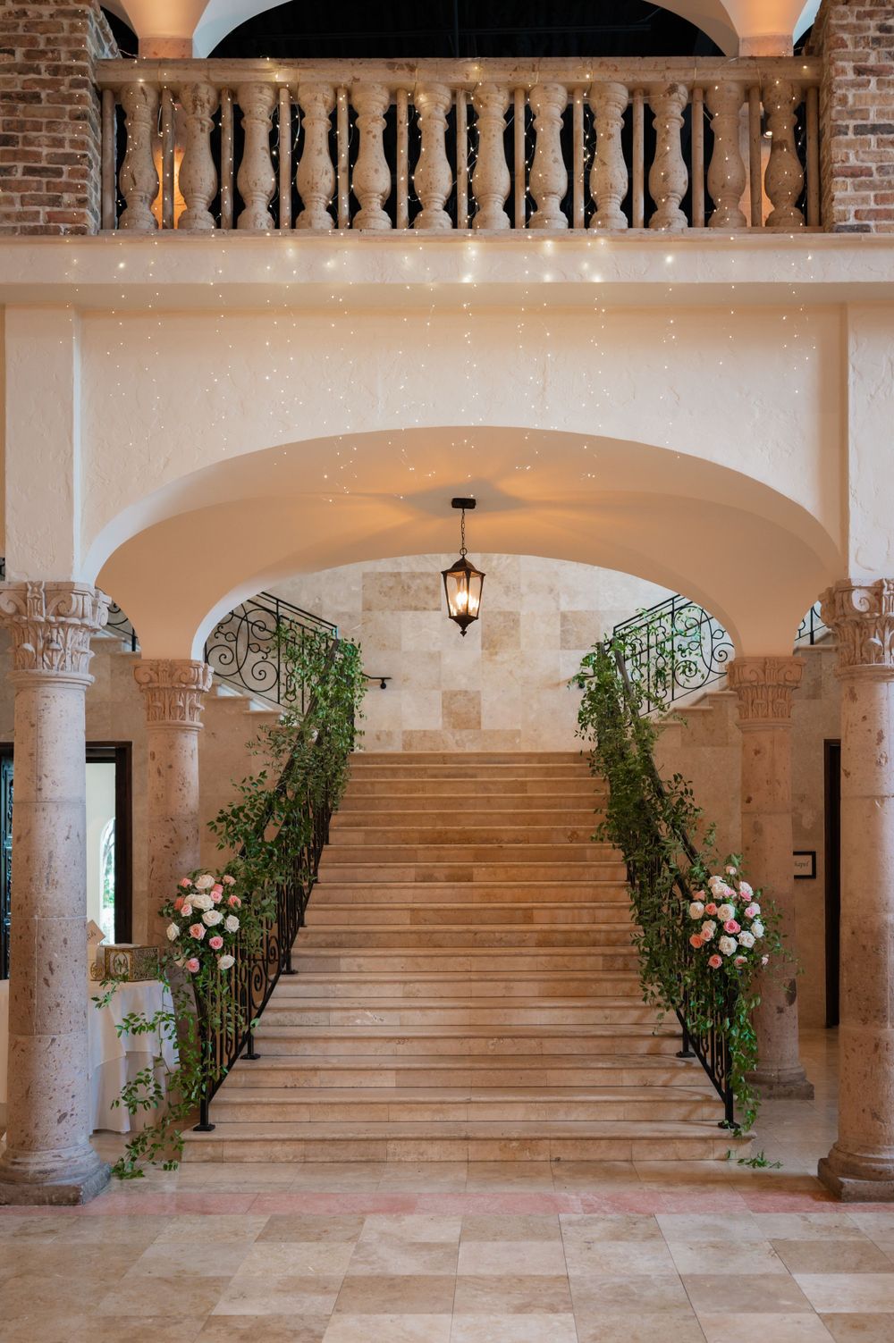 Grand staircase with brick archways and floral decorations in an elegant wedding venue.