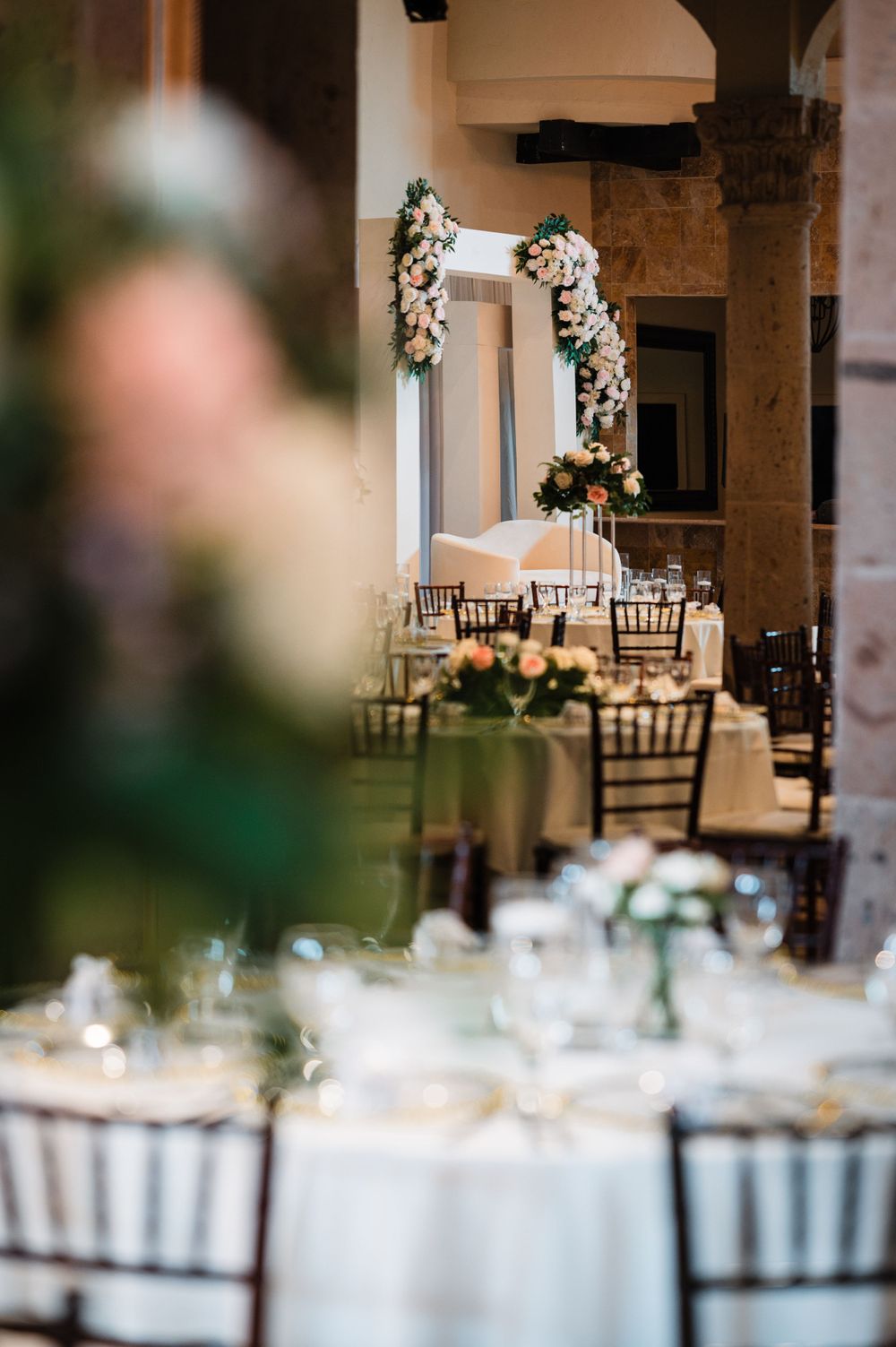 Wedding venue interior with elegant table settings and white floral arrangements.